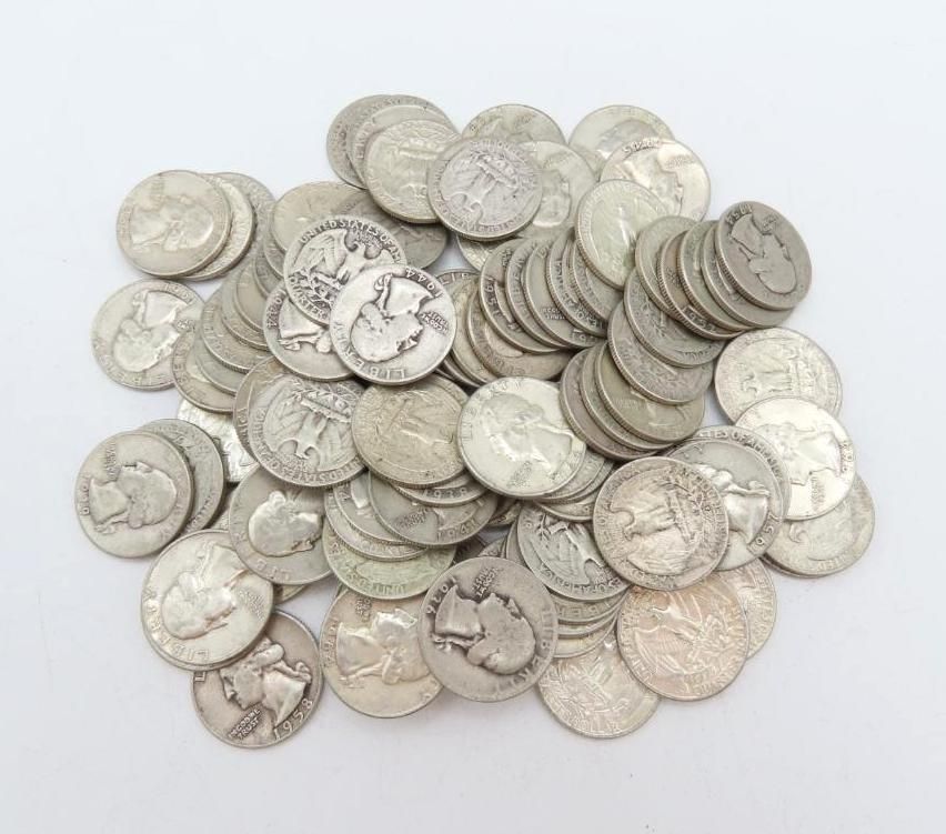 Pile of silver-colored coins, likely quarters, scattered on a white surface.