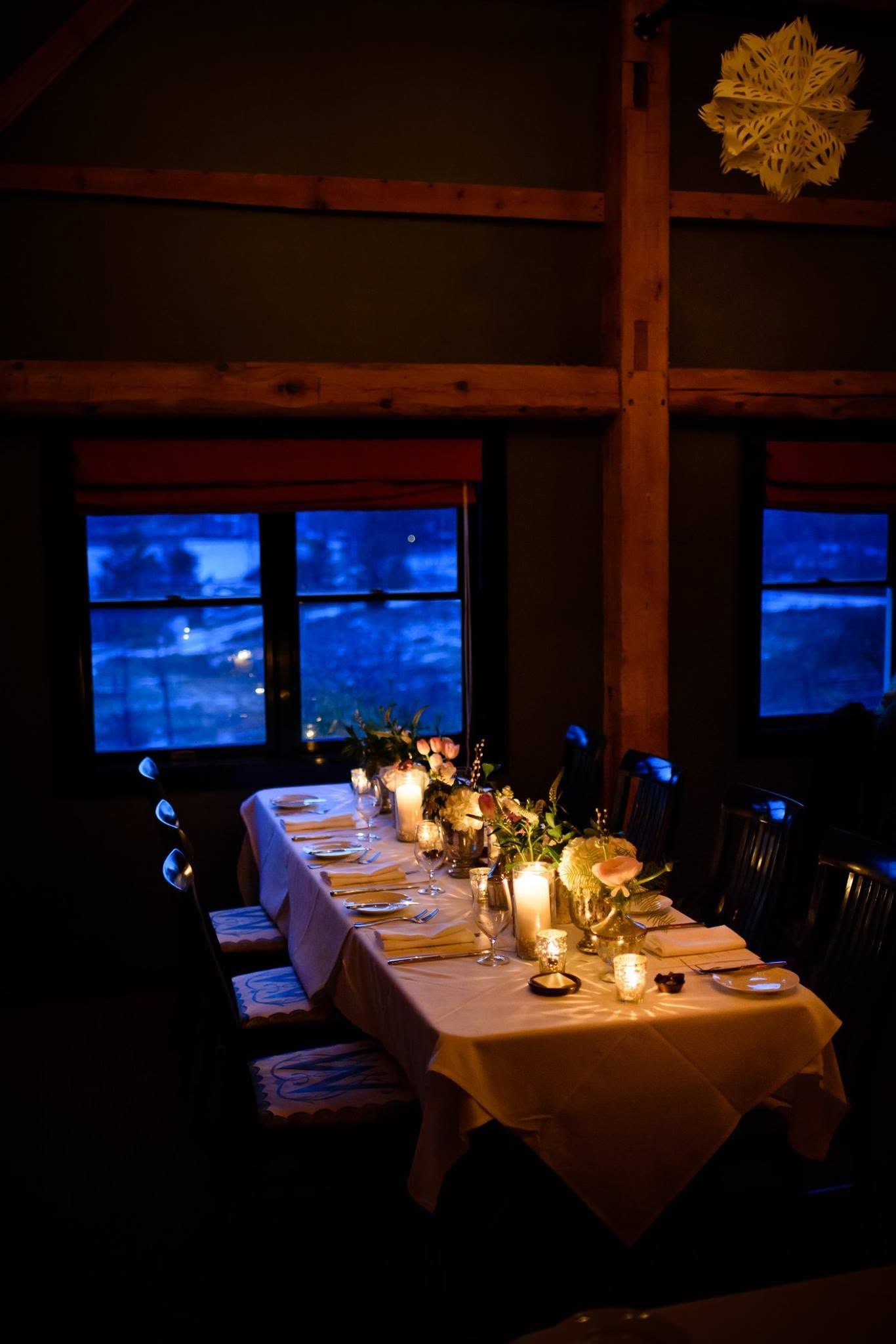 dining room with a candlelit table beside blue windows at night