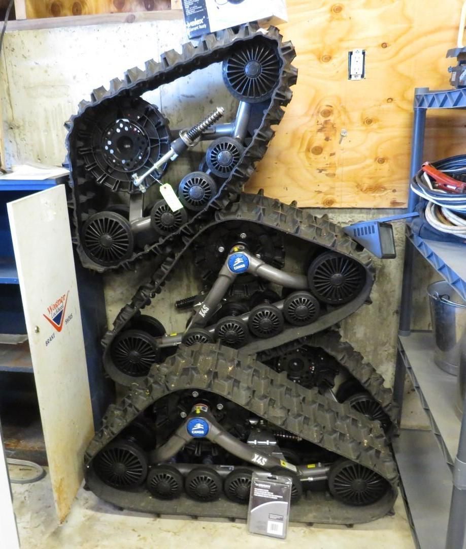 Three black snowmobile tracks stacked together in a storage area.