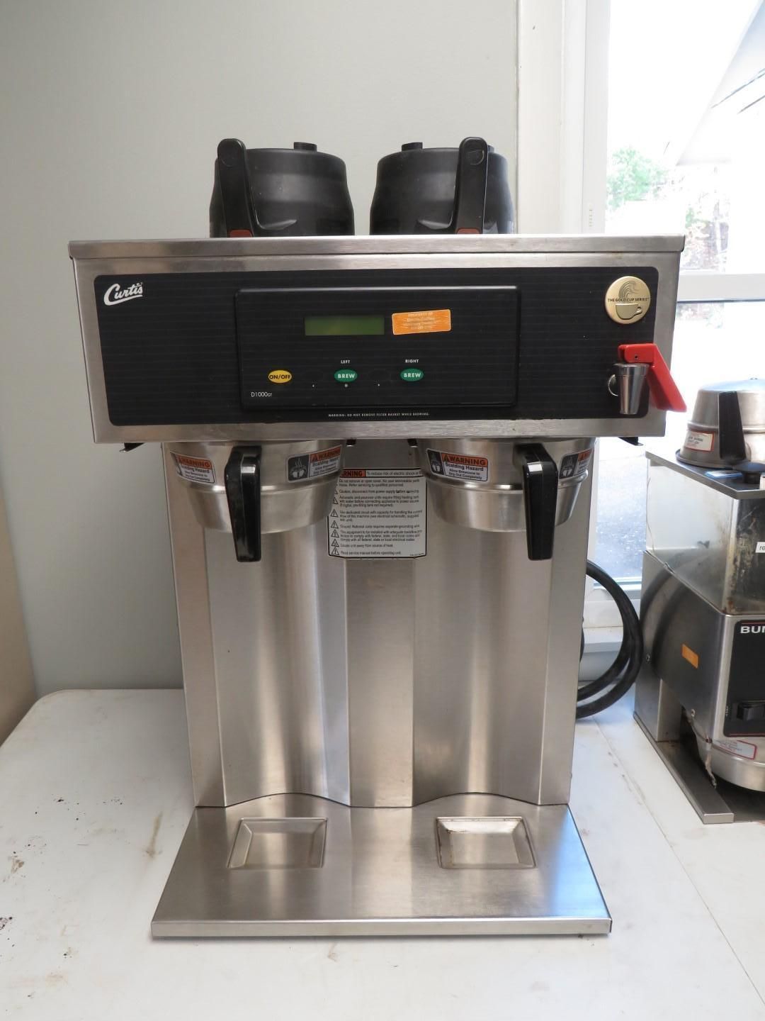 Stainless steel commercial coffee maker with two dispensers and black brewing station.