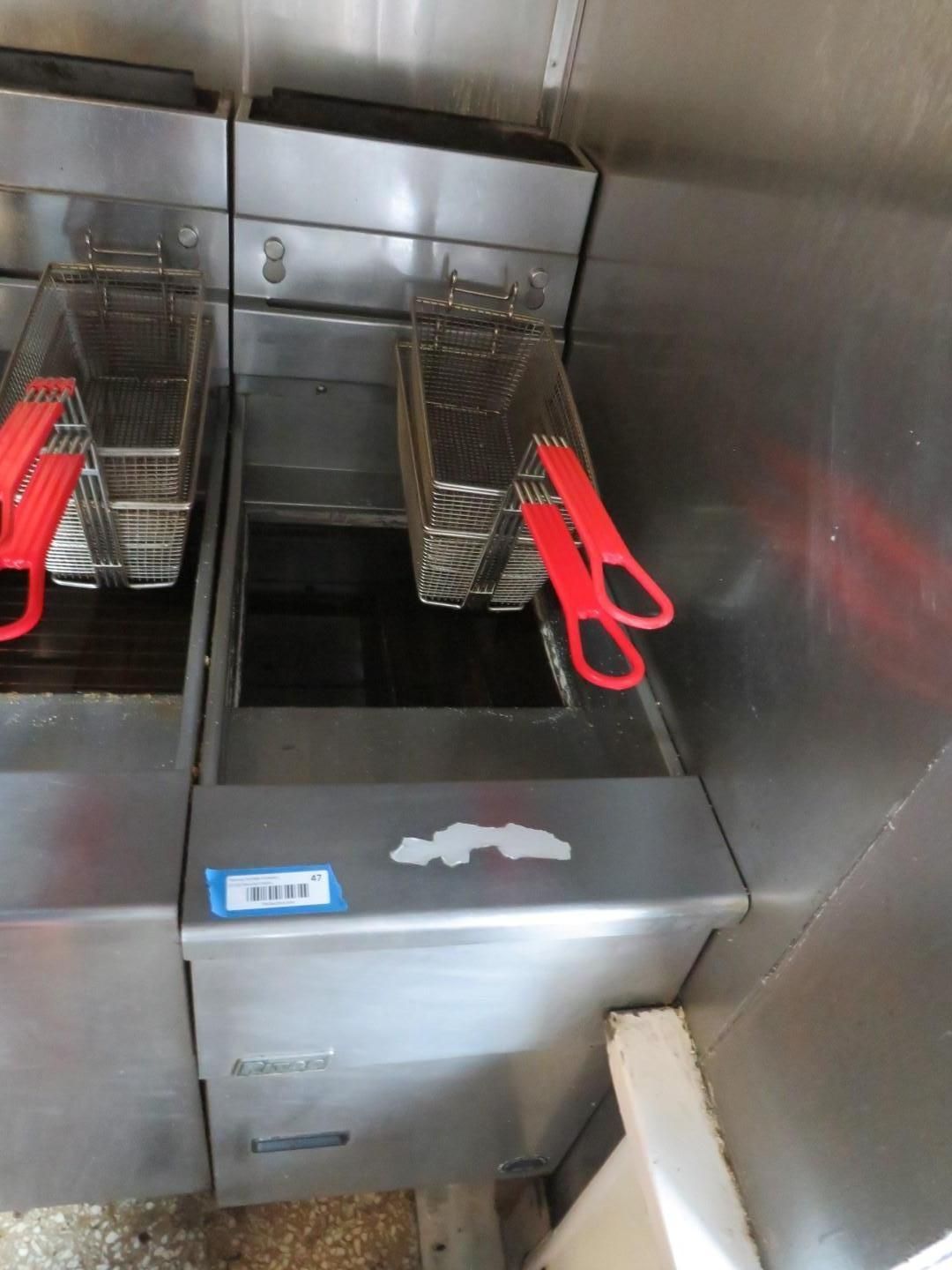 Two stainless steel deep fryers with fry baskets and red handles.