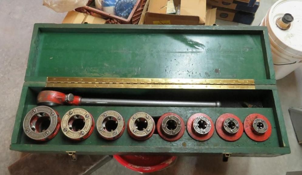 Green toolbox open, revealing pipe threading tools and dies.