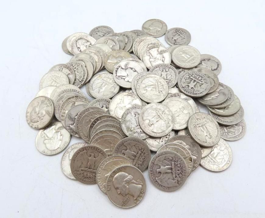 Pile of silver American quarters on a white surface.