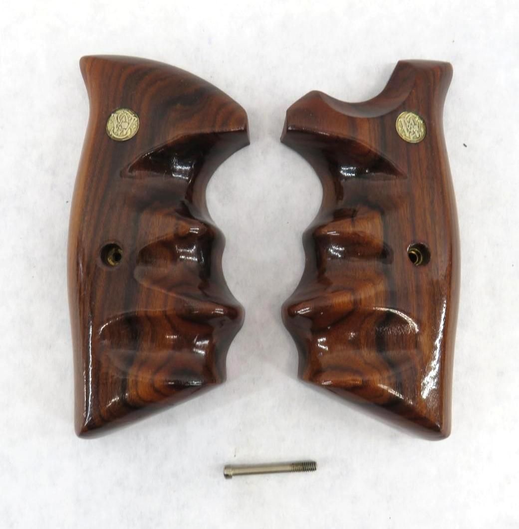 Pair of wooden handgun grips with gold medallions, separated with a pin.