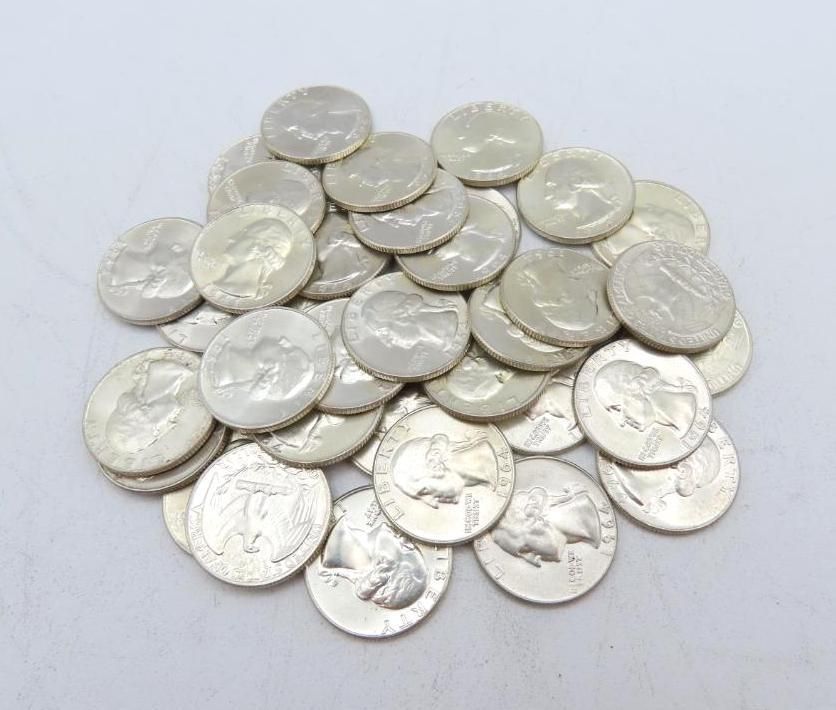 Pile of silver quarters on a white surface, showing the profiles of historical figures.