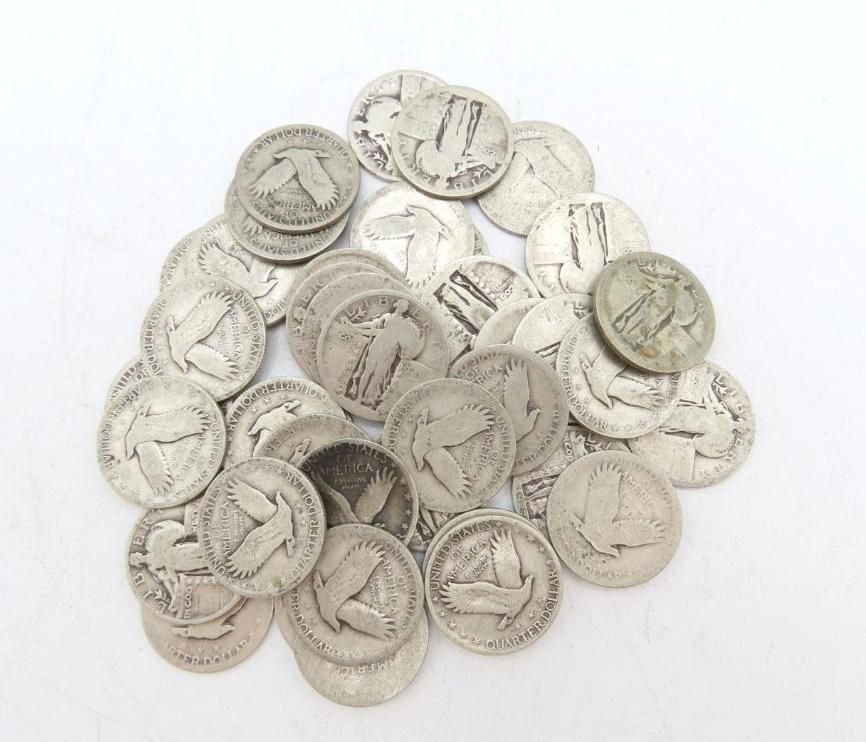 Pile of silver Mercury dimes on a white surface.