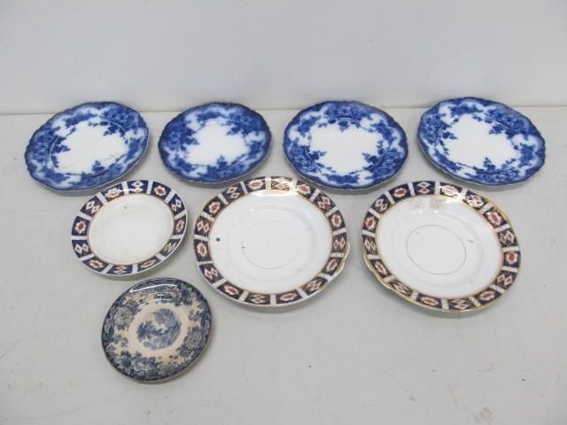 Assortment of antique blue and white and brown and white porcelain plates on a light surface.