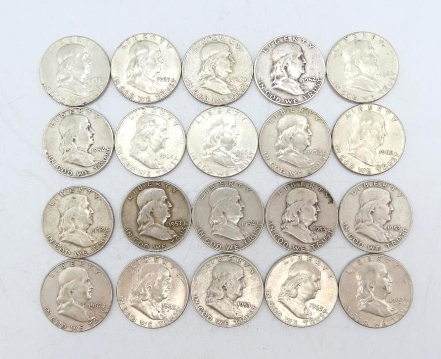 Twenty silver Franklin half dollars arranged on a white surface, all showing Benjamin Franklin's profile.
