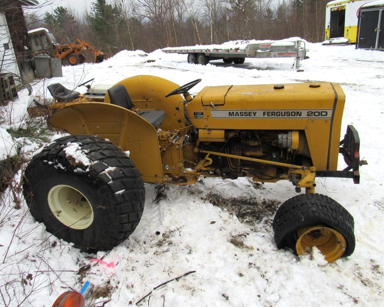 Yellow Massey Ferguson 210 tractor with large tires parked in snow-covered field.
