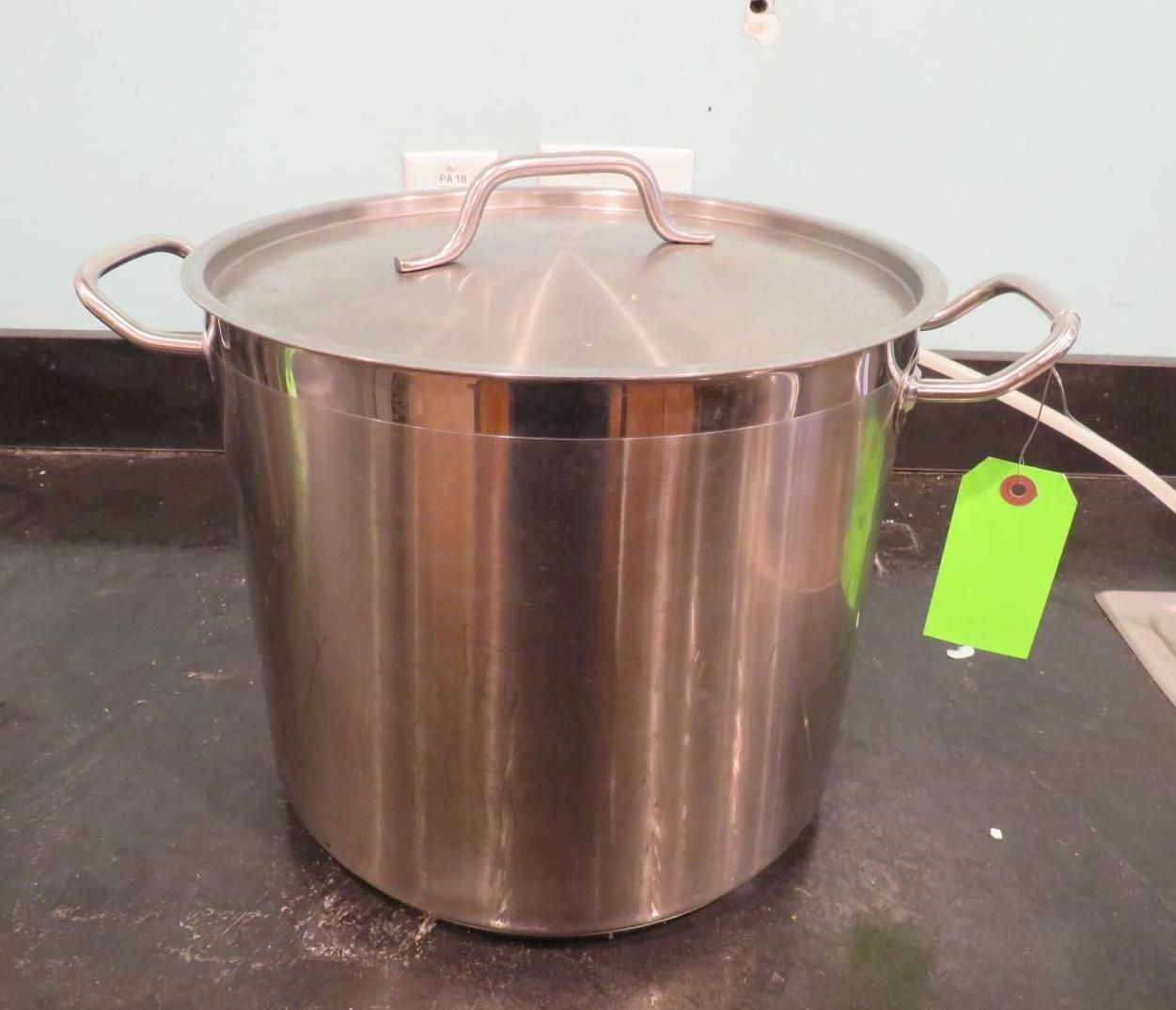 Stainless steel pot with lid on a dark countertop. Green tag attached.