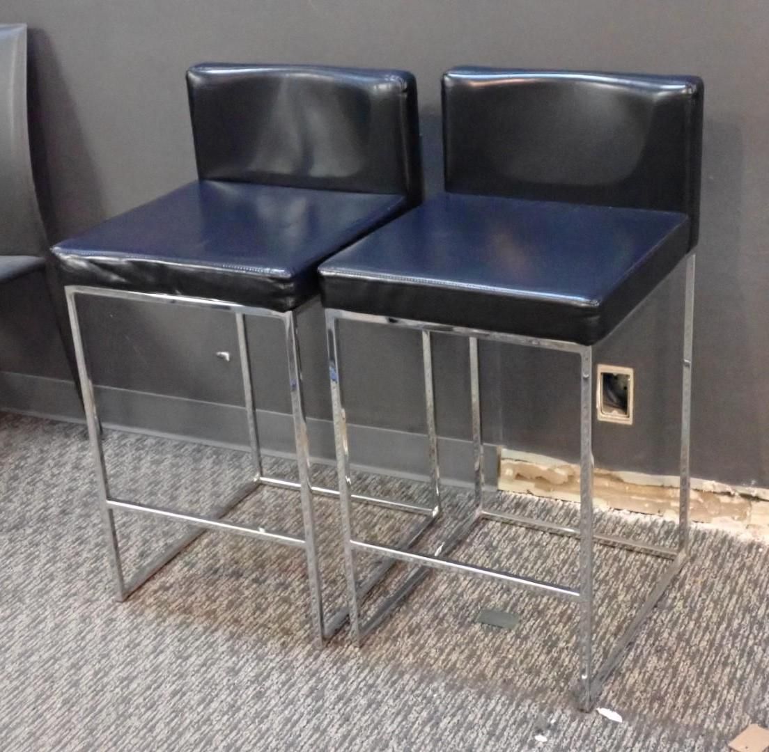 Two black leather bar stools with chrome frames.