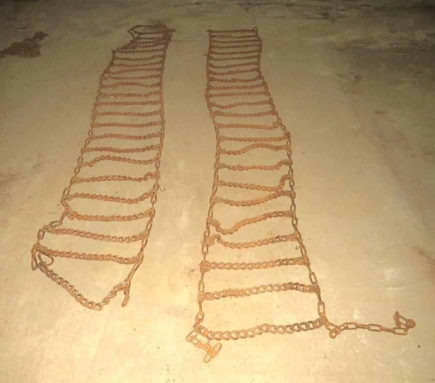 Two tire chains lying on a concrete surface.