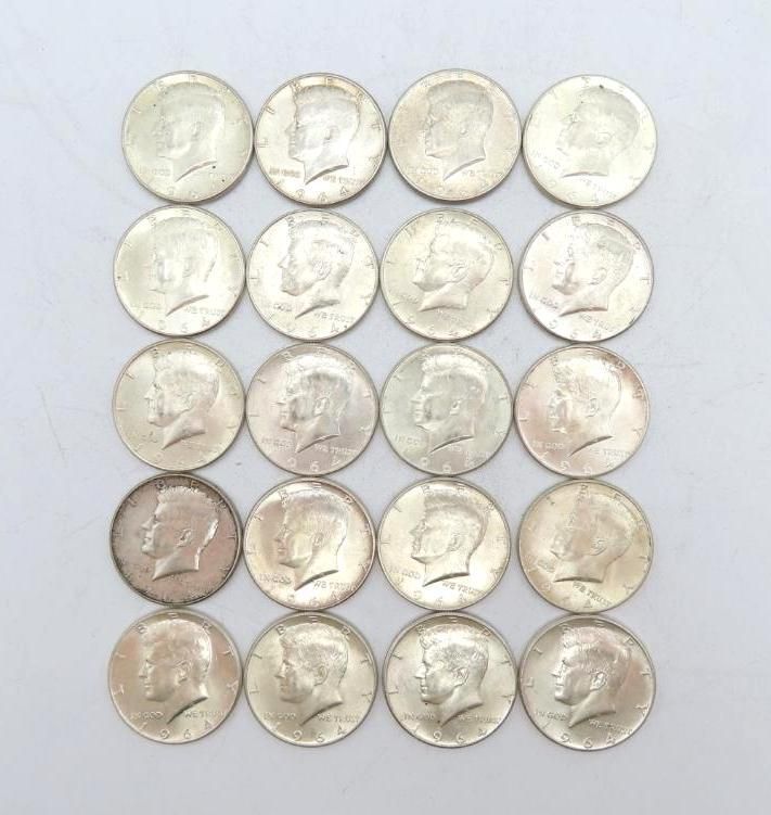 Twenty silver Kennedy half dollars arranged on a white surface, showing the bust of John F. Kennedy.