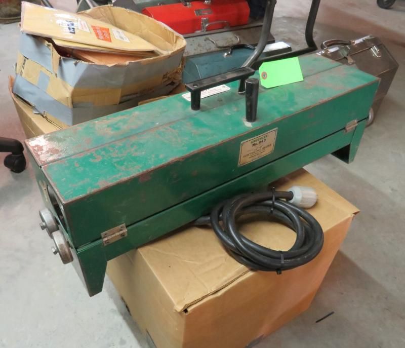 Green industrial machine with power cord, resting on a cardboard box.