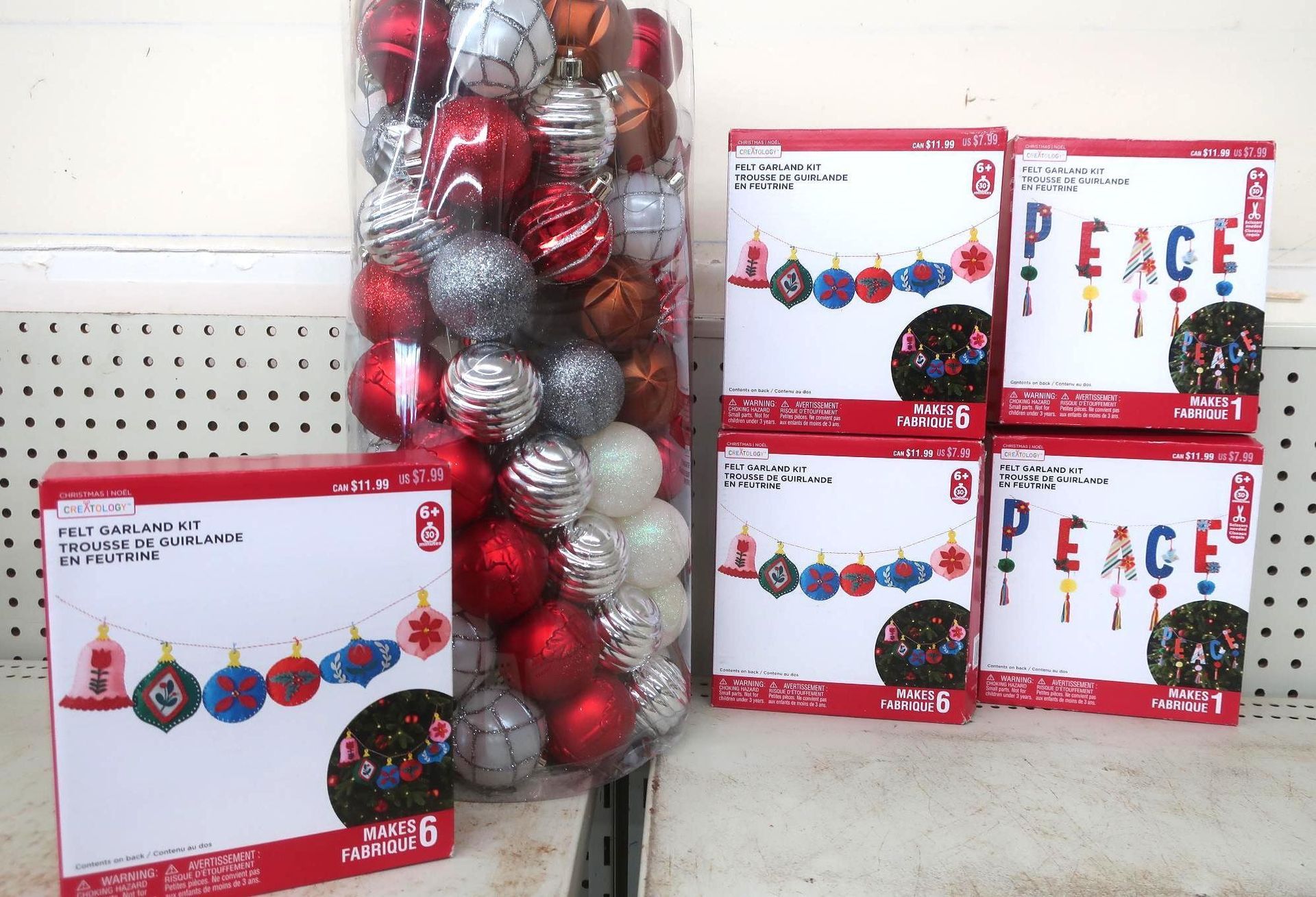 Christmas ornaments and string lights on a store shelf. Red, silver, and white baubles. Boxes of lights say