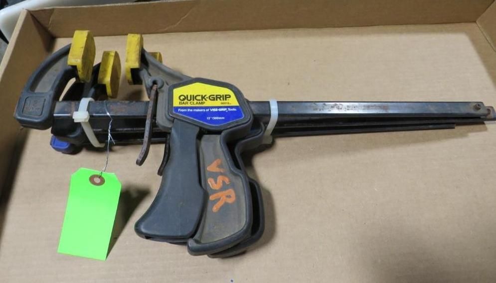 A QUICK-GRIP clamp, black and yellow, with a green tag.