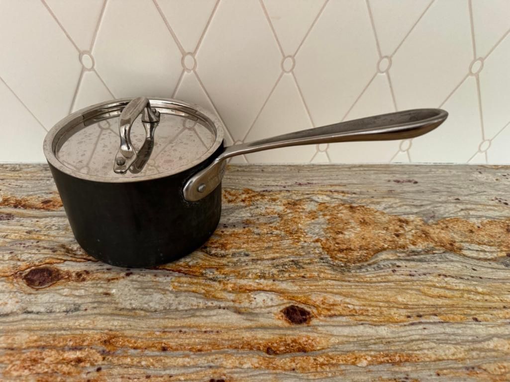 Small black saucepan with lid on a granite countertop.