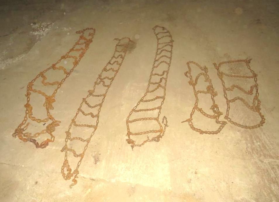 Chains lie on a light brown concrete floor, arranged in various elongated patterns.