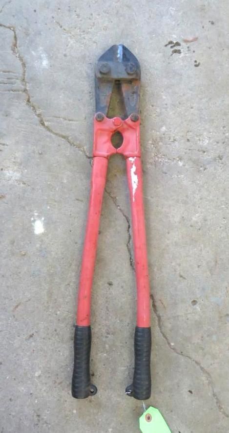 Red and black bolt cutters on a concrete surface.