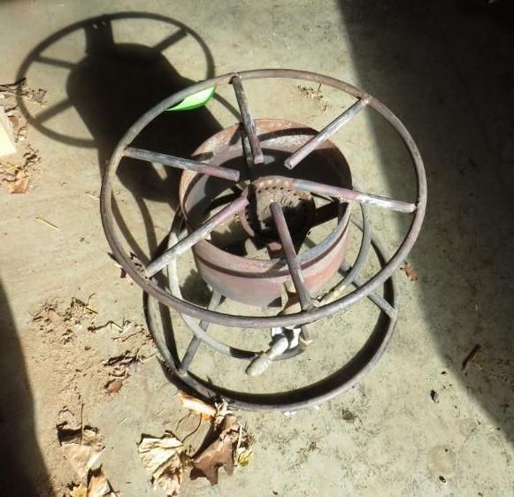 Metal propane burner, circular frame, with radial supports on concrete.