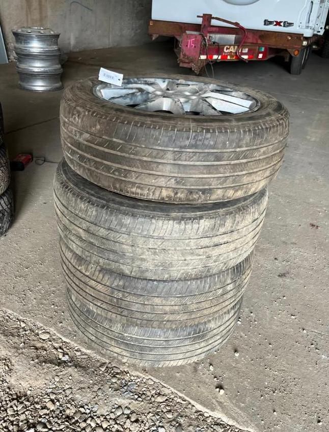 Three tires stacked; one on top has a silver rim.