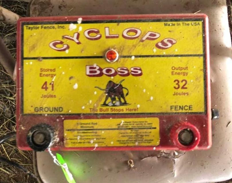 Electric fence energizer, yellow with red trim, labeled