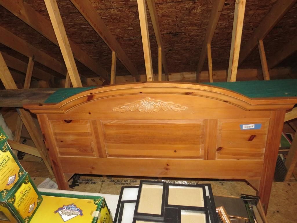 Wooden headboard in an attic, with green fabric trim, surrounded by wooden beams.