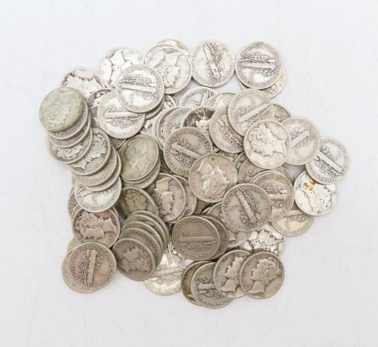 Pile of old silver nickels scattered on a white surface, showing details of the coins.