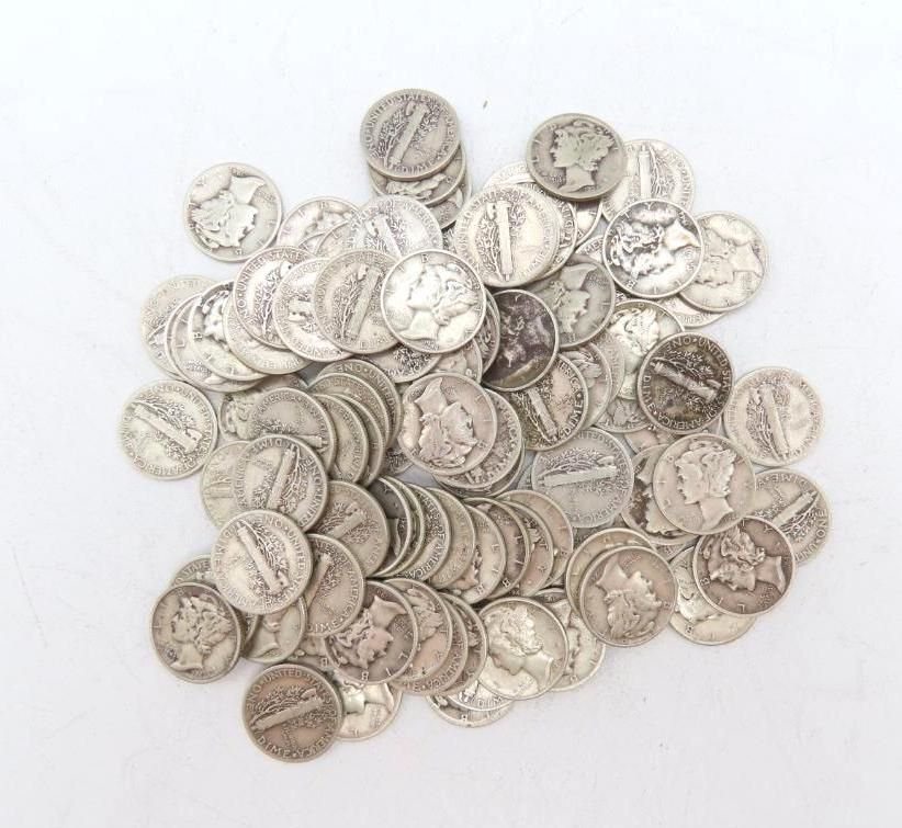 Pile of silver Mercury dimes on a white surface.