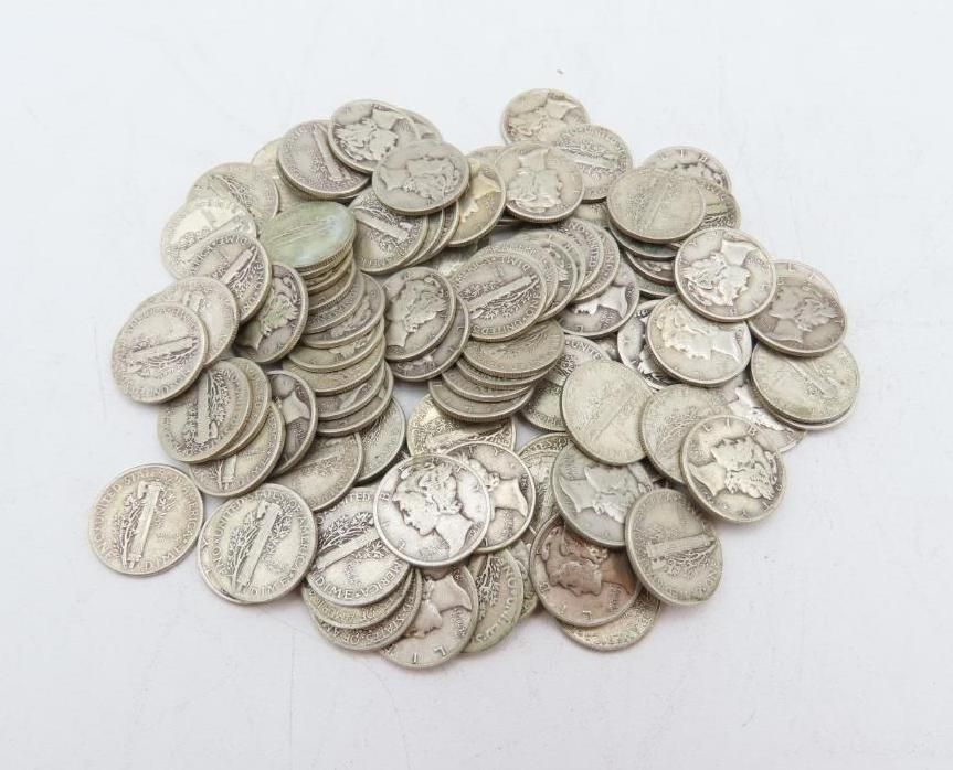 Pile of silver Mercury dimes on a white surface.