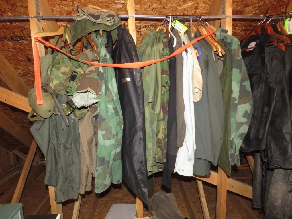 Clothing rack in an attic, displaying various coats and military camouflage attire.
