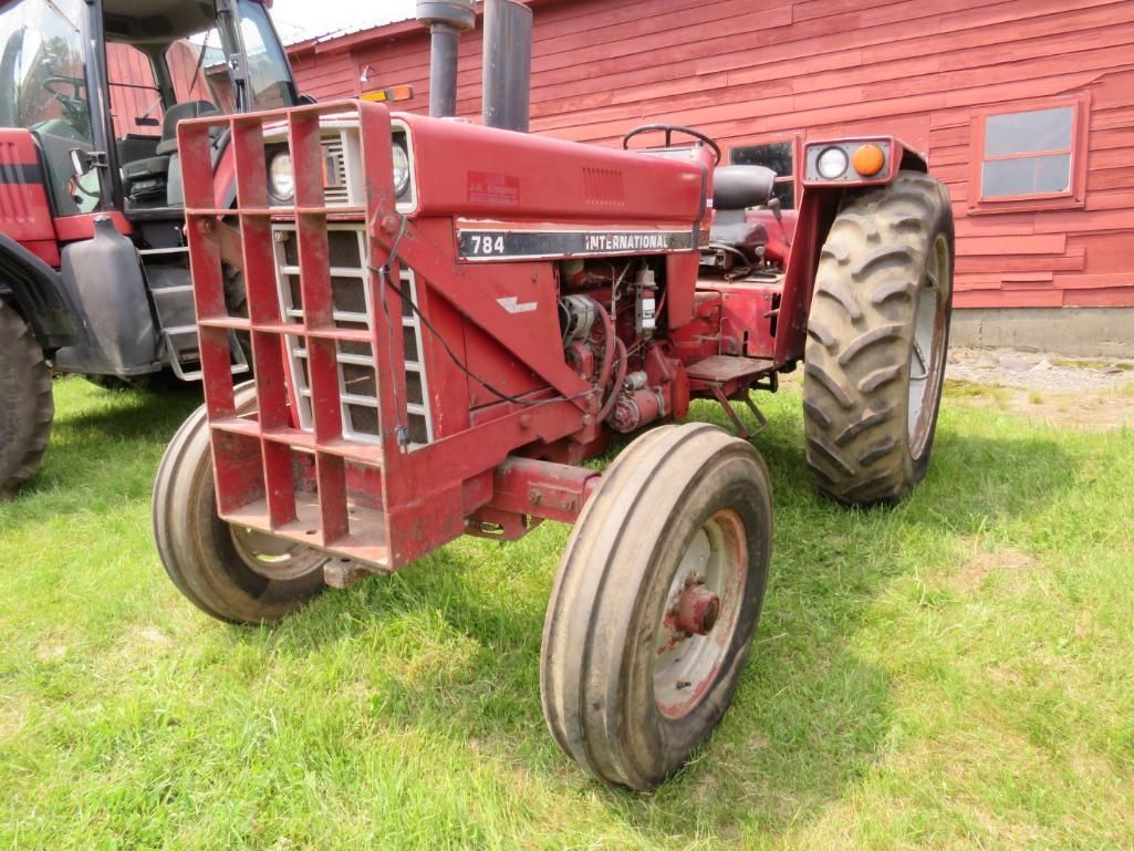 Red International Harvester tractor on green grass in front of a red building.