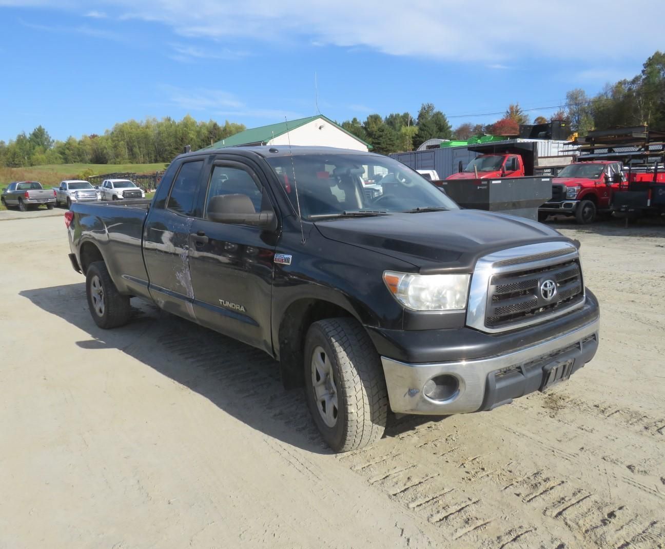 Black Toyota Tundra pickup truck in a gravel lot on a sunny day.
