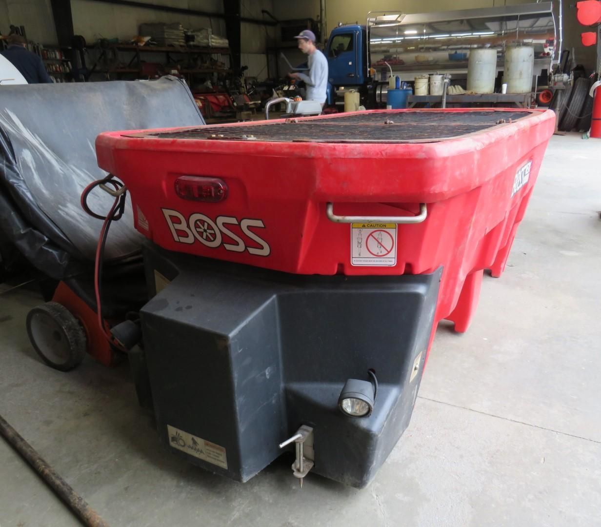 Red BOSS salt spreader on wheels, in a garage.