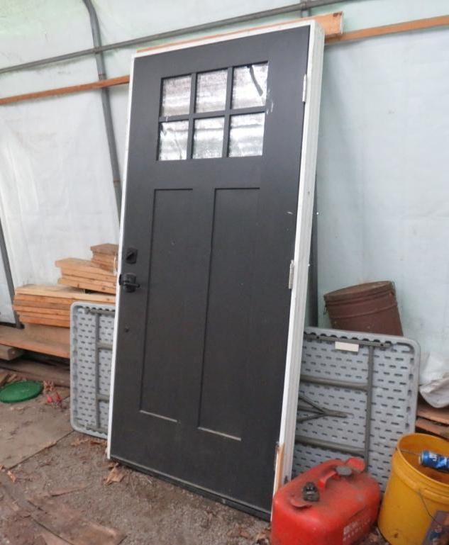 Black door with glass panes, leaning against a wall.