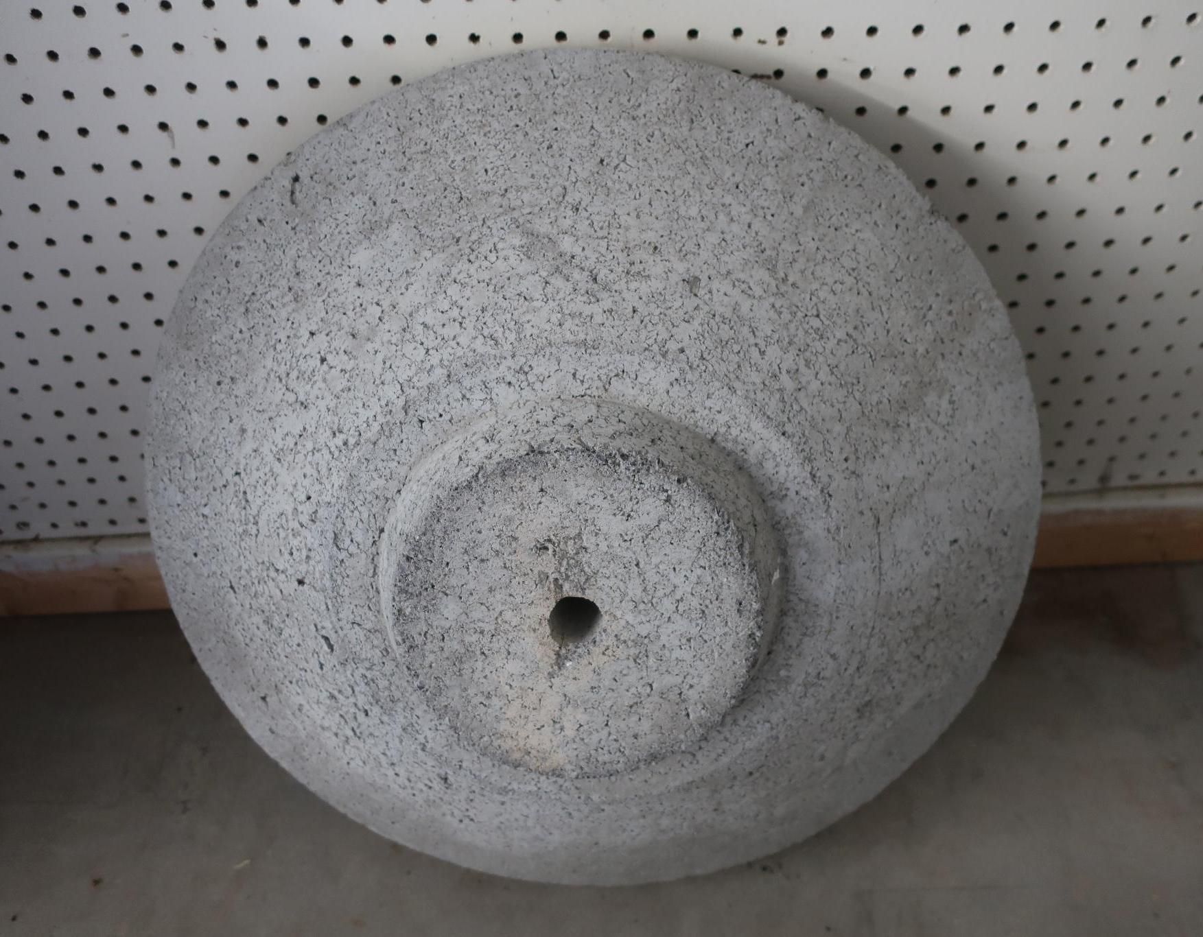 Gray stone grinding wheel with a central hub and a small hole, against a white speckled backdrop.