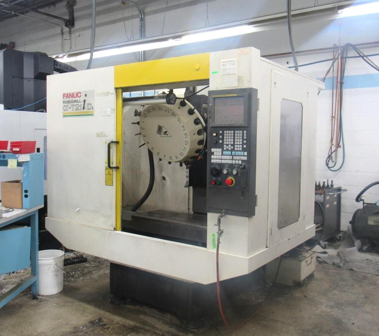 CNC milling machine with a yellow accent. Inside a factory setting.