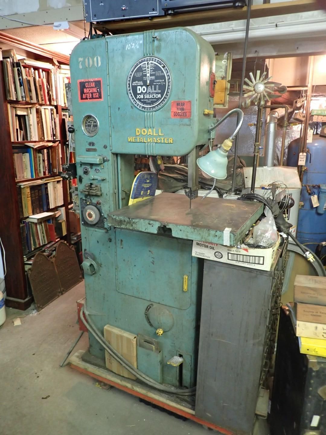 A teal-colored, industrial bandsaw machine.