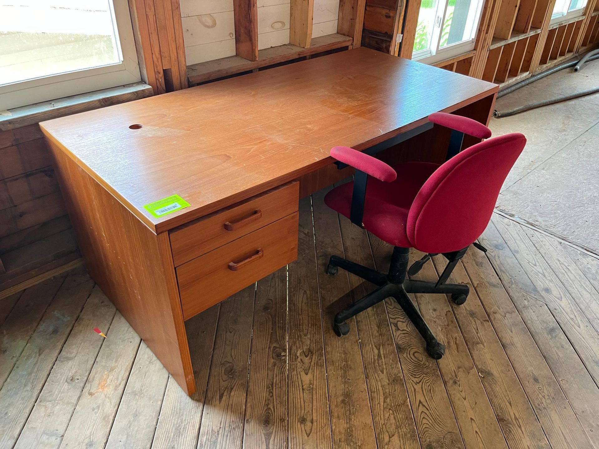 Office desk with red chair, drawers on left.