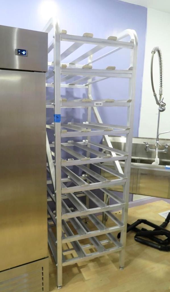 Stainless steel shelving unit next to a tall refrigerator, in a room with light blue walls.