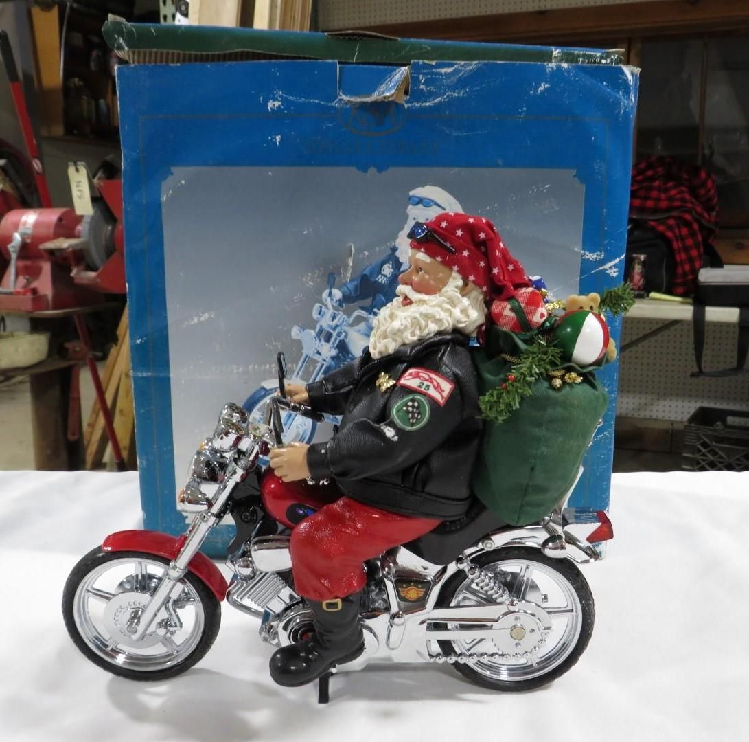 Santa Claus on a red motorcycle, with a green sack of gifts.