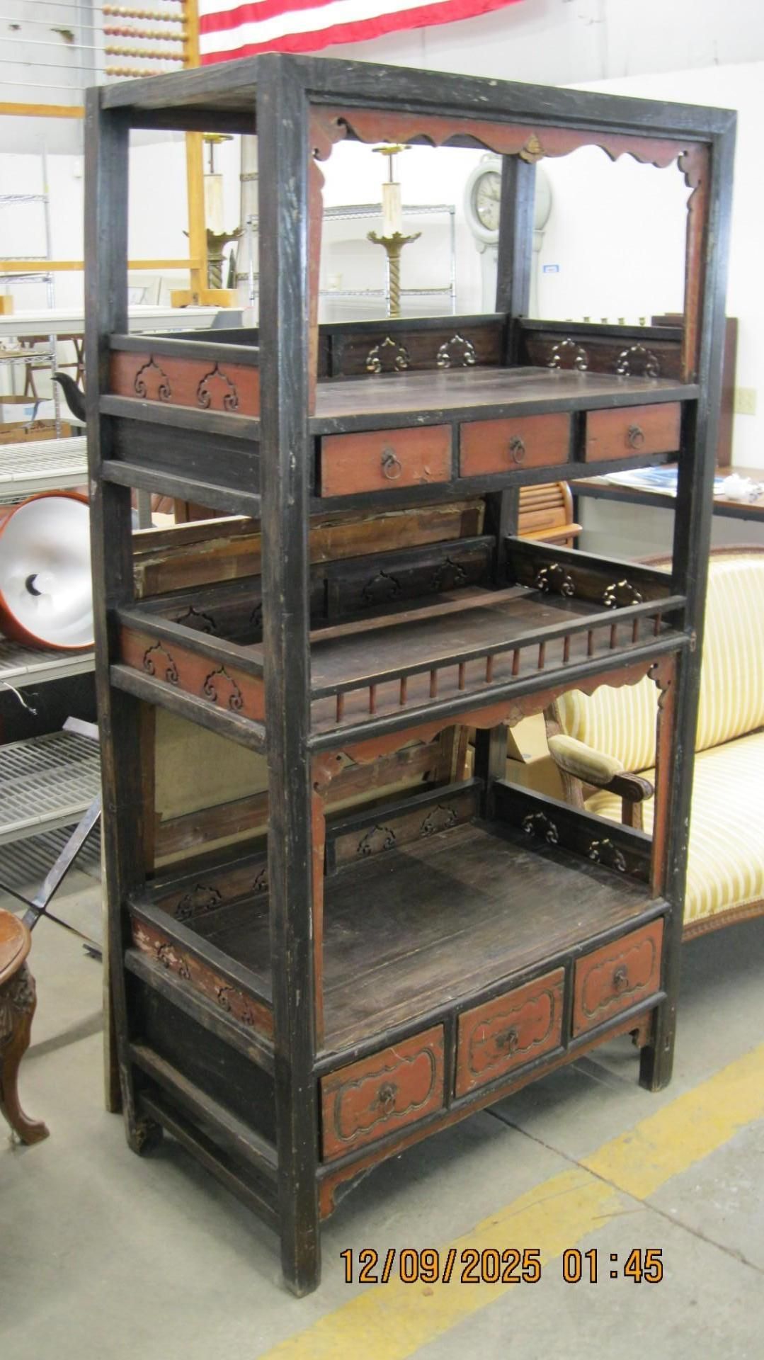 Tall, dark, Asian-style shelving unit with drawers and decorative trim.