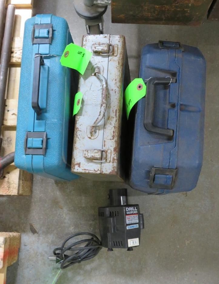 Four tool cases and a black power adapter on a concrete floor.