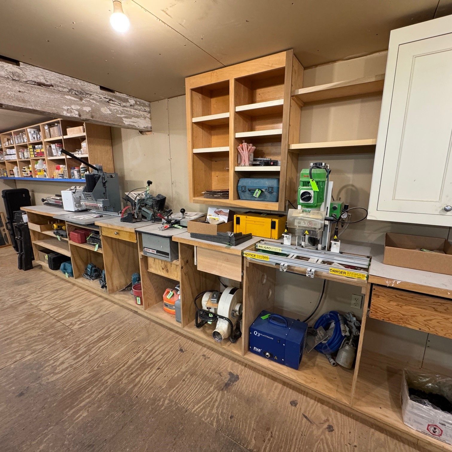 Wooden garage workshop shelves and workbench with tools, boxes, and a green machine unit