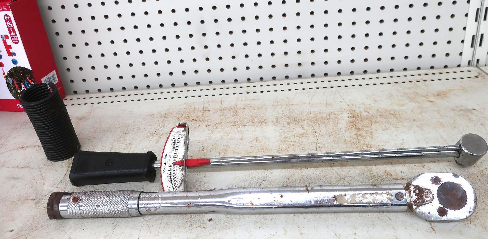 Tools on a shelf, including a torque wrench, a breaker bar, and a socket.