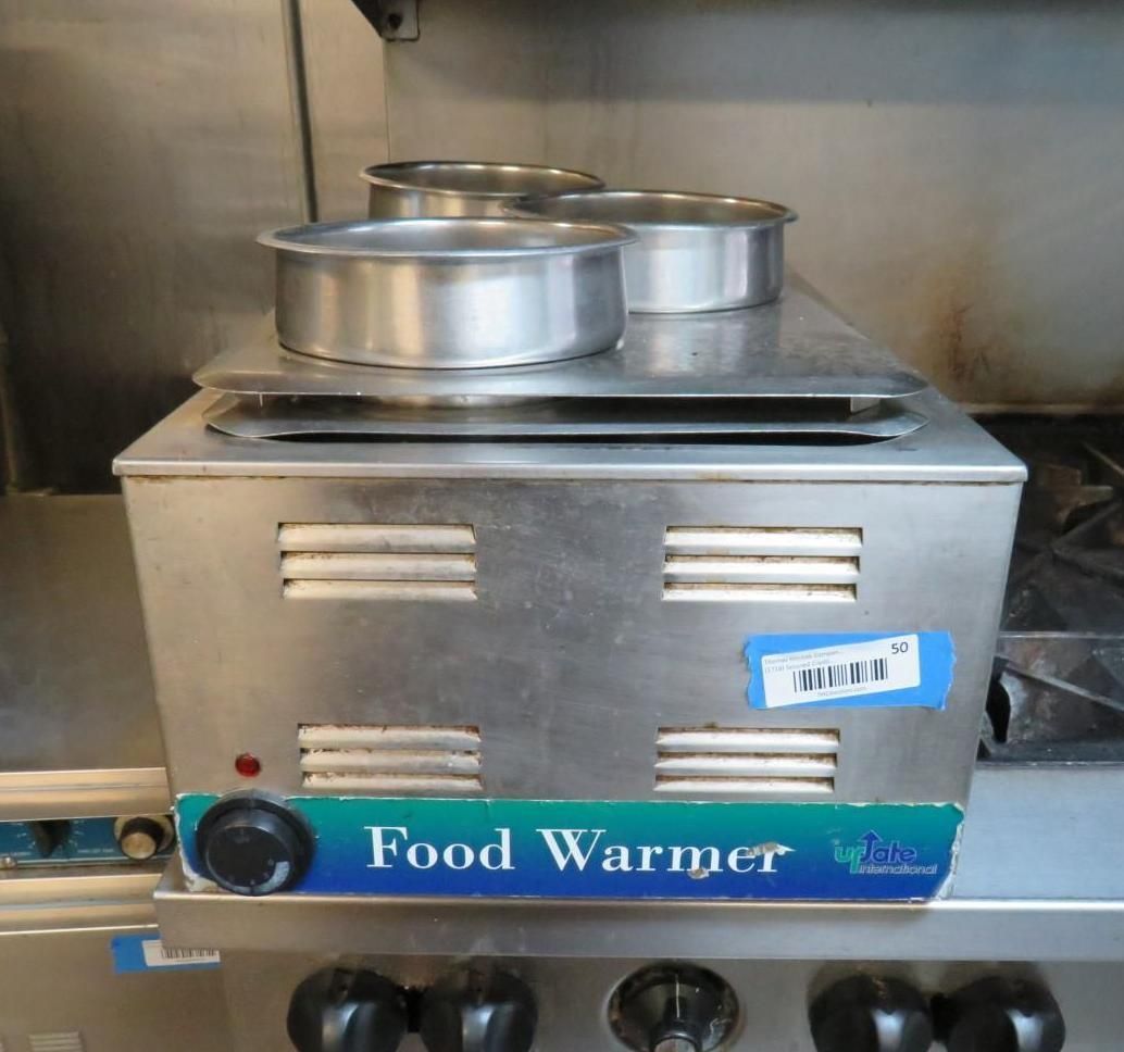 Stainless steel food warmer on a stove with three metal serving rings on top.