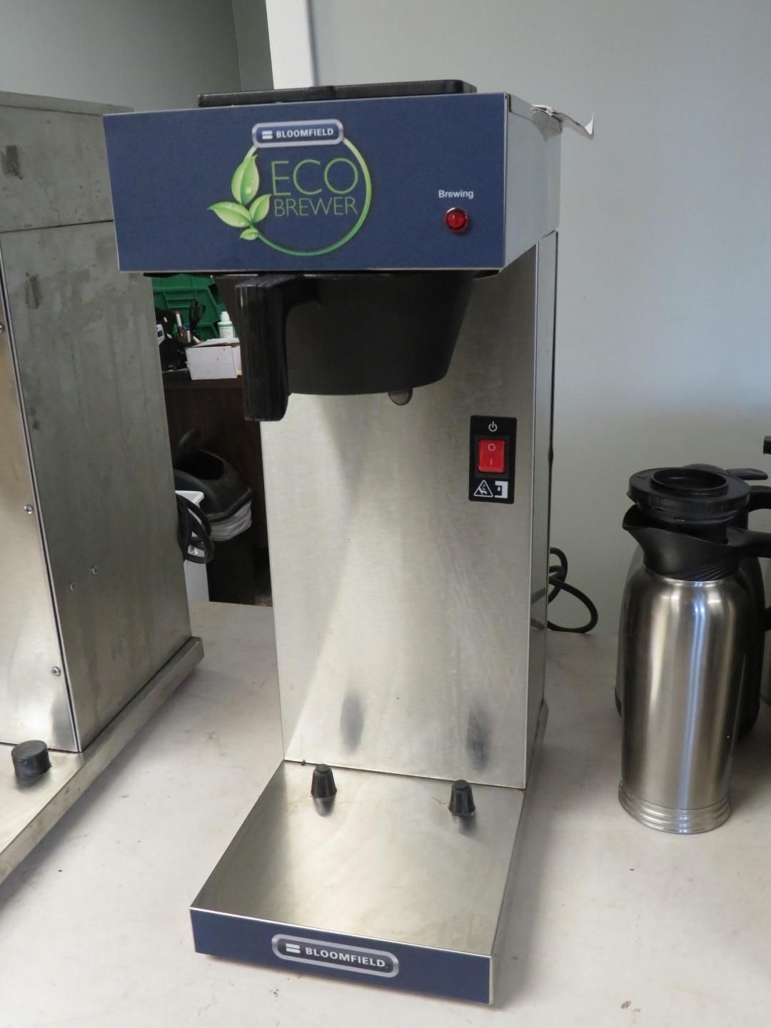 Stainless steel commercial coffee maker with a blue eco-friendly logo, next to a thermal carafe.