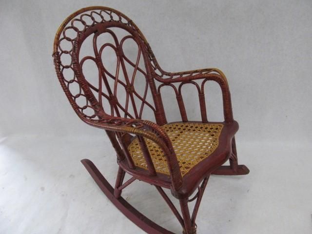 Red wicker rocking chair with woven seat, on a white background.