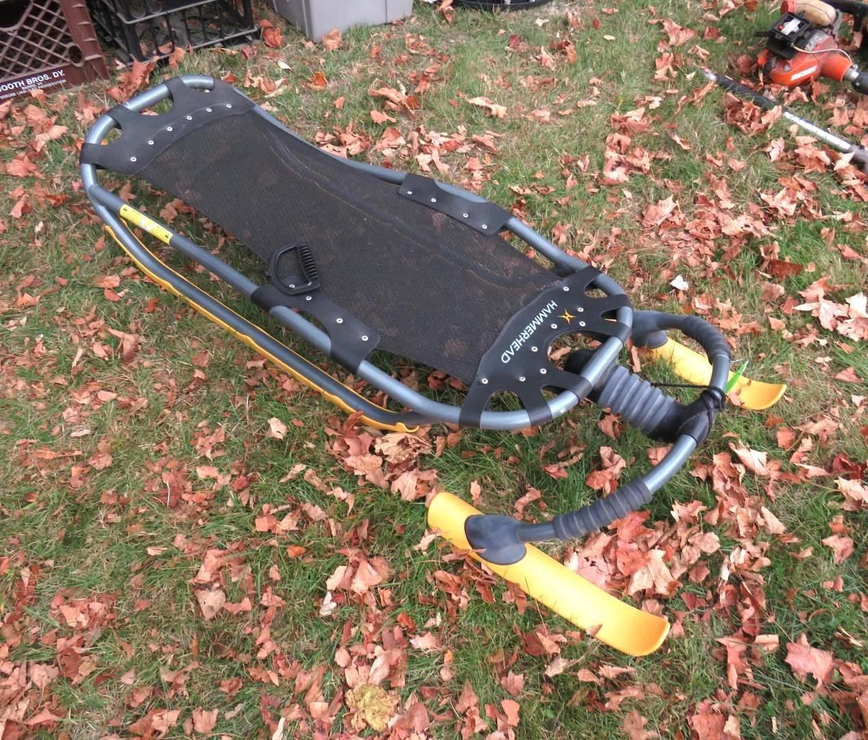 A black and yellow toboggan sits on grass.