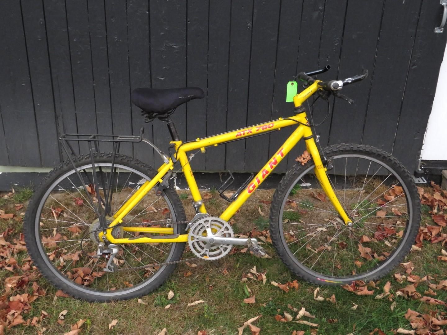 Yellow Giant mountain bike parked outdoors near a dark wall.